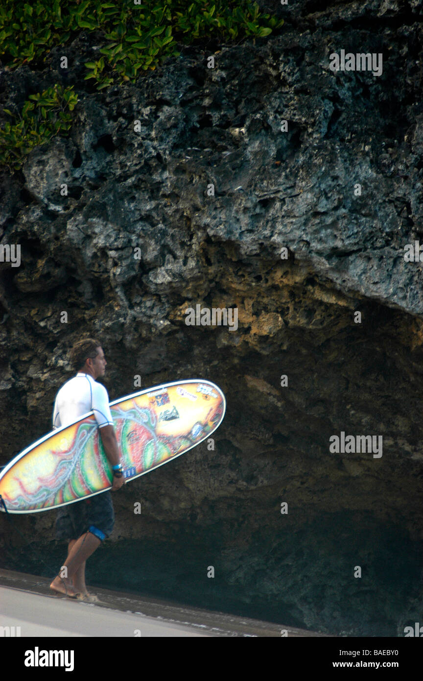 Ein Surfer stehen am Strand mit seinem Brett auf hohen Felsen vor dem Eintritt in das Meer Stockfoto