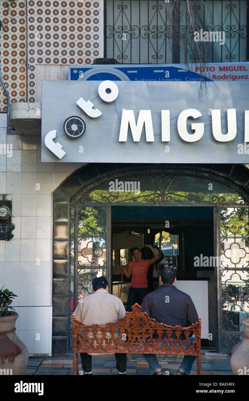 Mexiko-La Paz-zwei Männer sitzen auf Bank außerhalb Fotografie Geschäft Frau Mitarbeiter winken Stockfoto