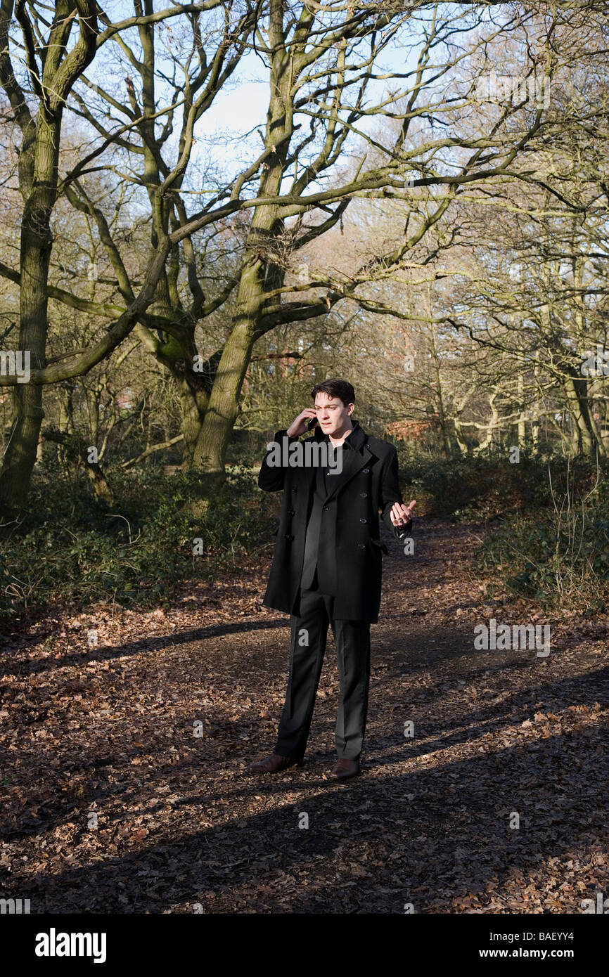 Junger Geschäftsmann, Wandern in den Wäldern mit einem Handy Stockfoto