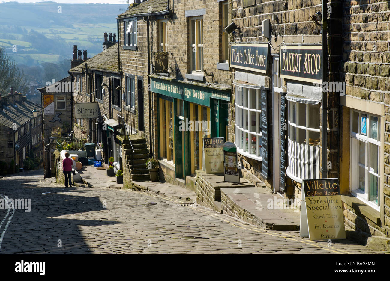 Frau zu Fuß hinunter die gepflasterten Hauptstraße von Haworth, West Yorkshire, England UK Stockfoto