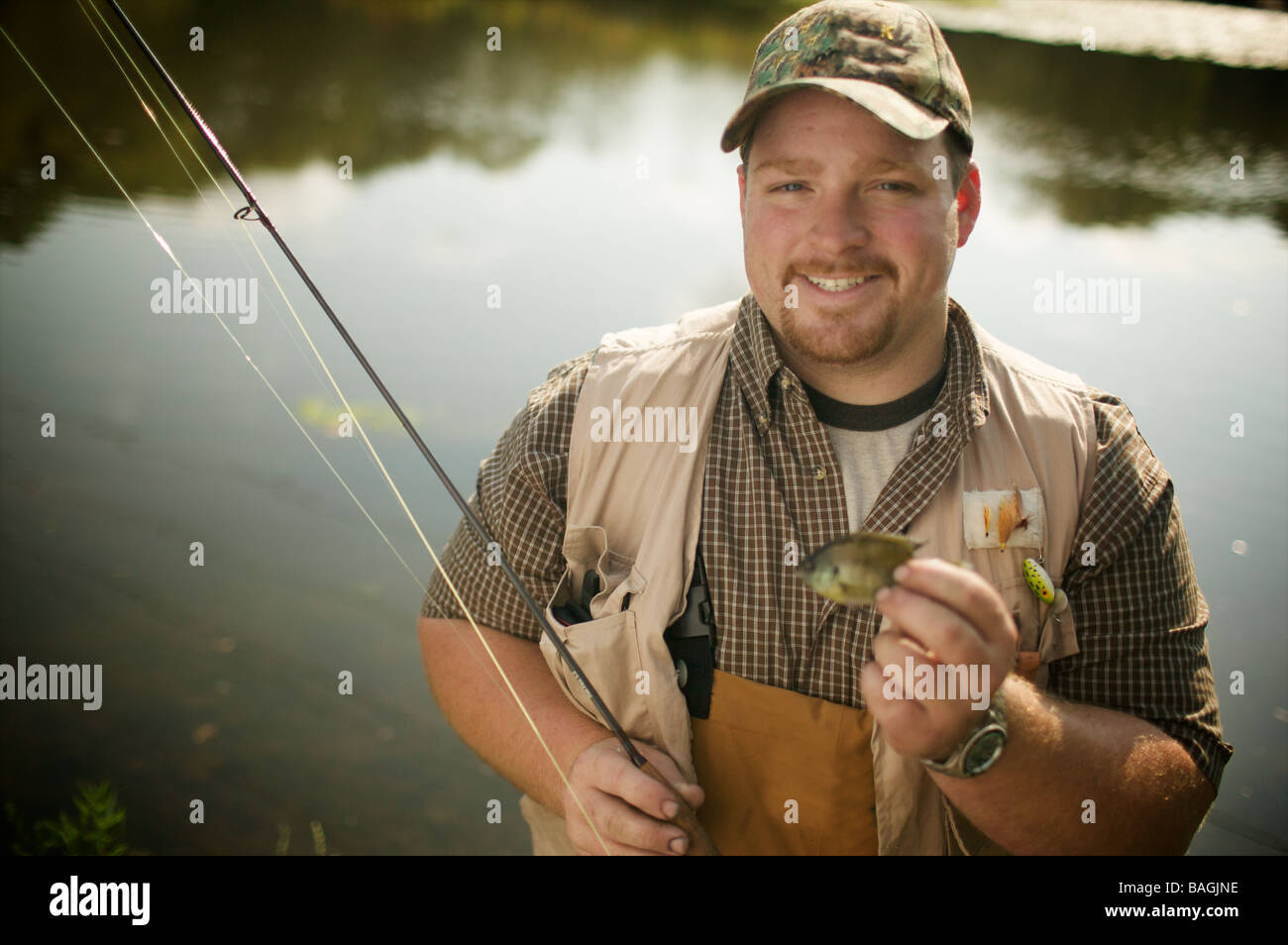 Großer Mann stolz darauf, ein teeny tiny Itty fangen bitty kleine Fische. Eine Studie an Kontrasten. Großer Kerl hat einen winzigen Fisch gefangen. Stockfoto