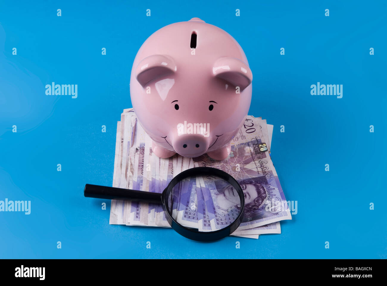 Sparschwein mit Lupe über britisches Geld Stockfoto
