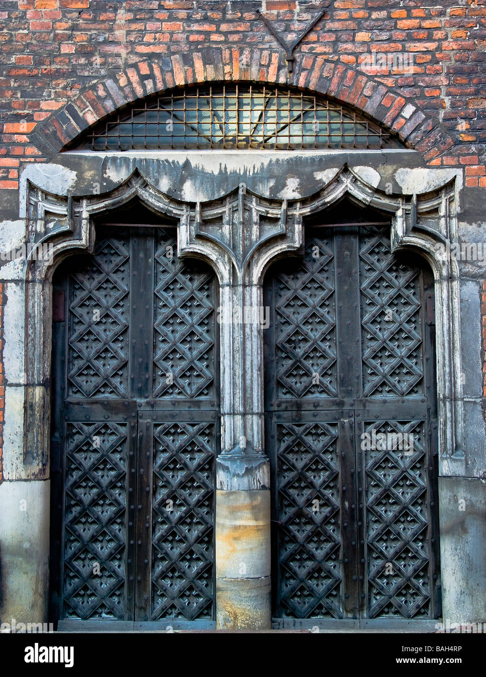 Alte mittelalterliche Tor aus Stein und Holz hergestellt. Teil der historischen Kathedrale mit Ziegelwänden. Stockfoto