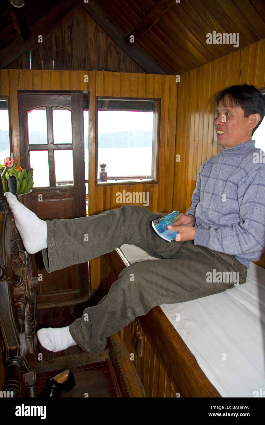 Vietnamesisch Boot Captin Lenkung mit den Füßen in Ha Long Bay Vietnam Stockfoto