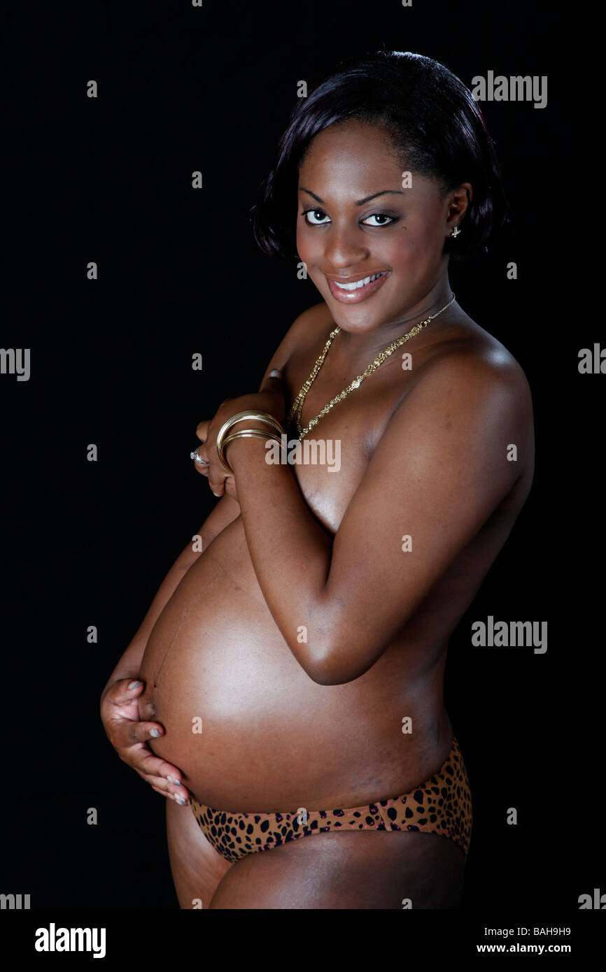 hübsche schwarze schwangere Mädchen auf schwarzem Hintergrund Stockfoto