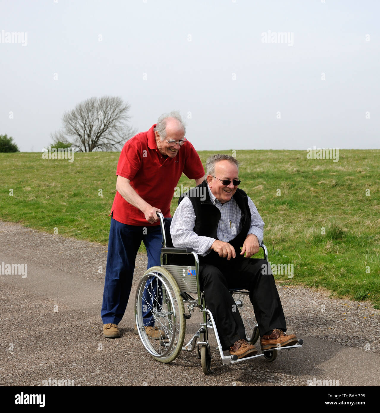 Ältere Männer eins mit begrenzter Mobilität und Rollstuhl Benutzer gedrängt von seinem Betreuer die englische Landschaft zu genießen Stockfoto