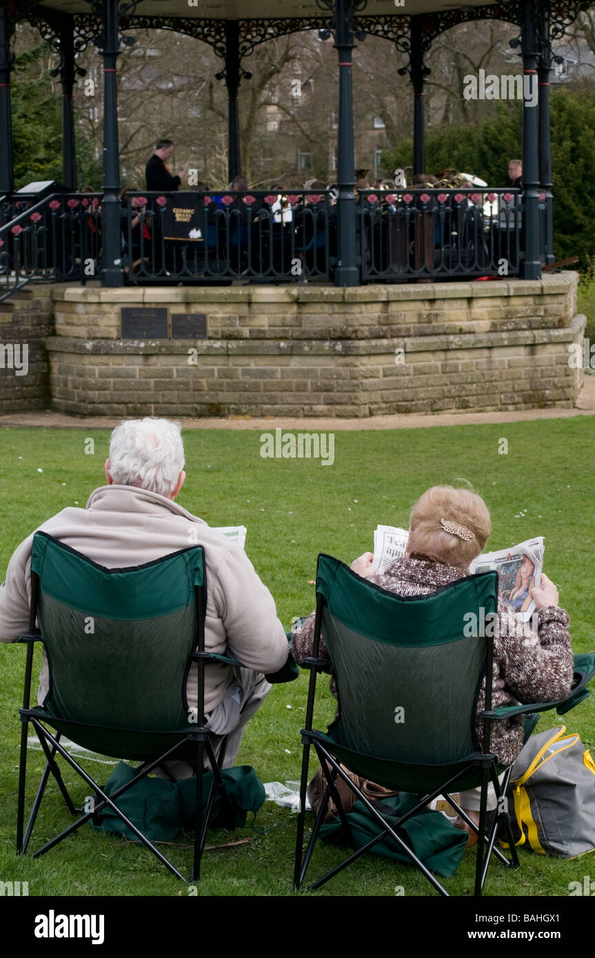Elderley paar sitzen ein Trommler-und Pfeiferkorps in Buxton Pavilion Gardens in Derbyshire Peak District England anhören Stockfoto
