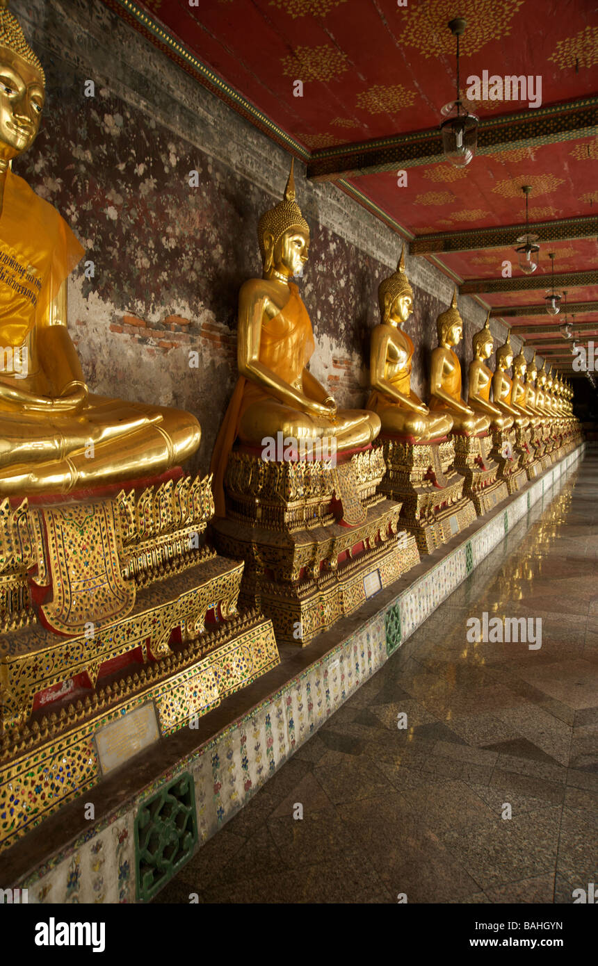 Eine Reihe von Gold Buddhastatuen säumen die Galerien im Wat Suthat Tempel in Bangkok Thailand Stockfoto