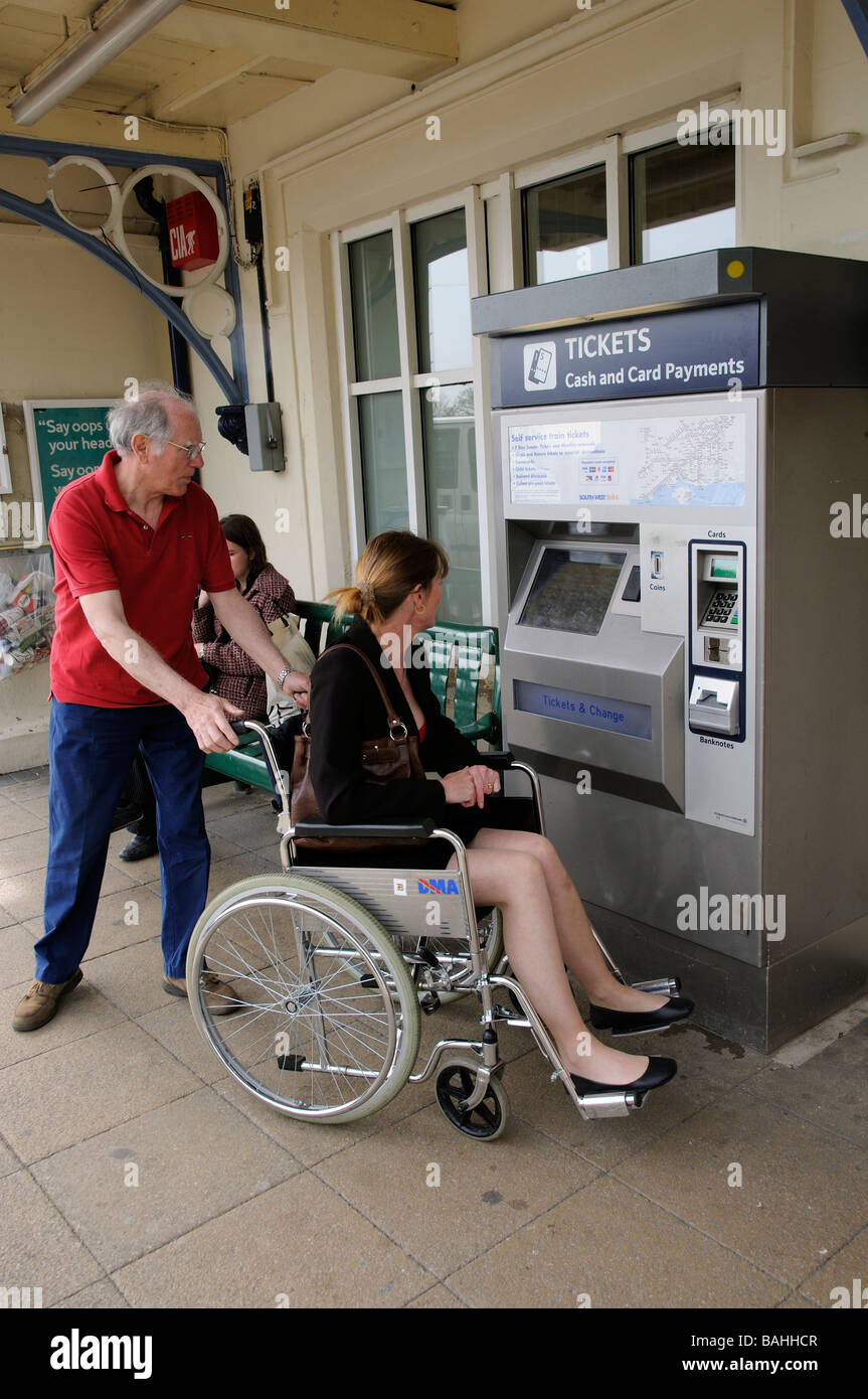 Rollstuhlfahrer und Betreuer kaufen ein Bahn-ticket Stockfoto