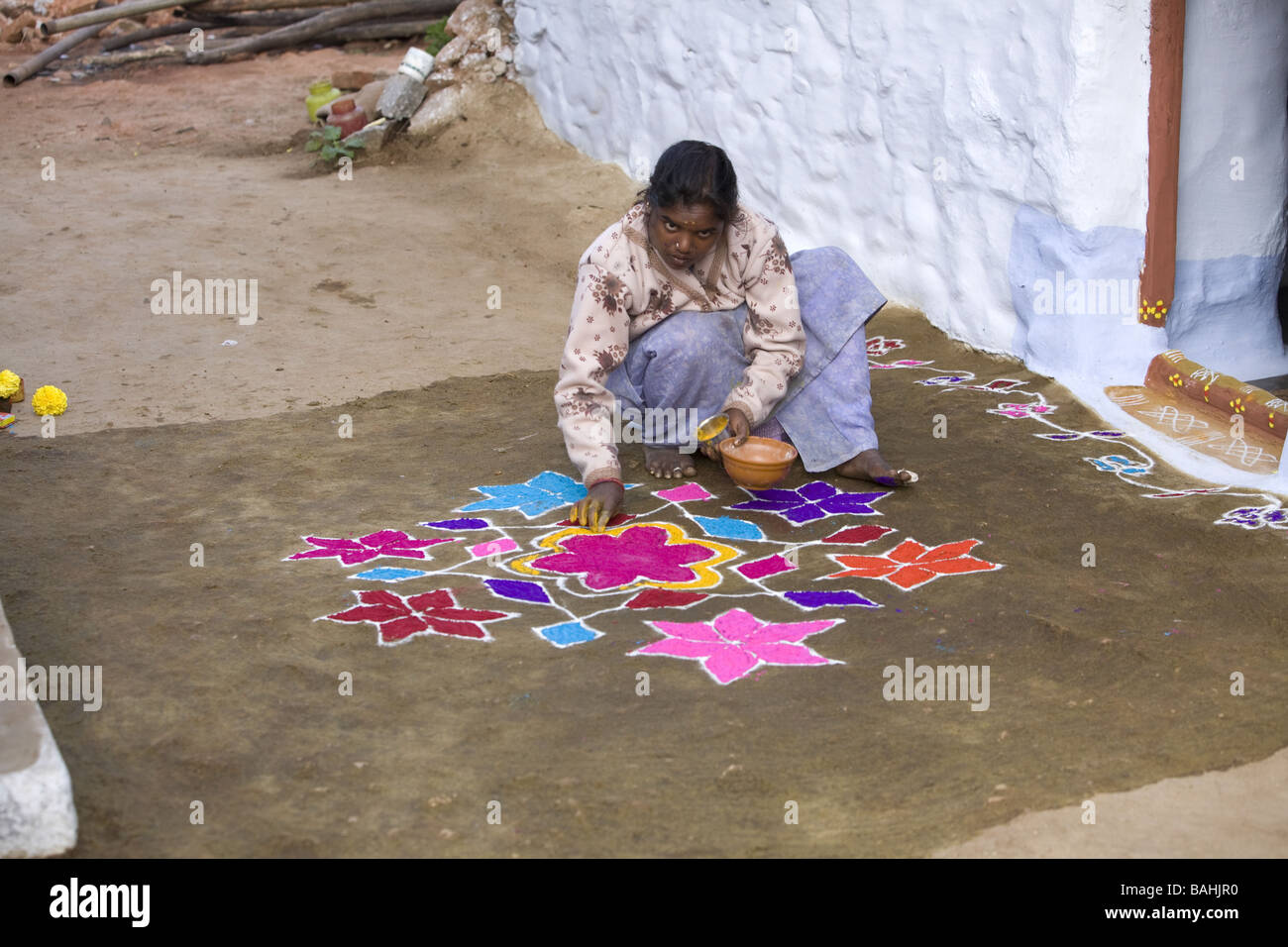 Inderin, Räucherstäbchen in ein Angebot von Blumen und Kuhmist auf ein Rangoli Design in einer indischen Straße Stockfoto