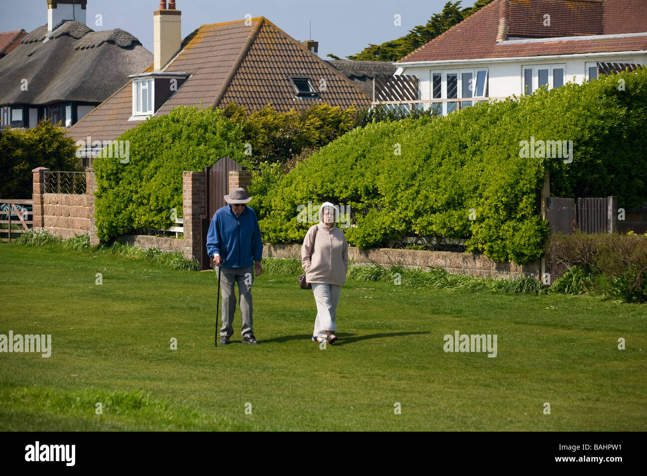 Ältere Paare wandern entlang der greensward bei Ferring, Sussex, UK Stockfoto