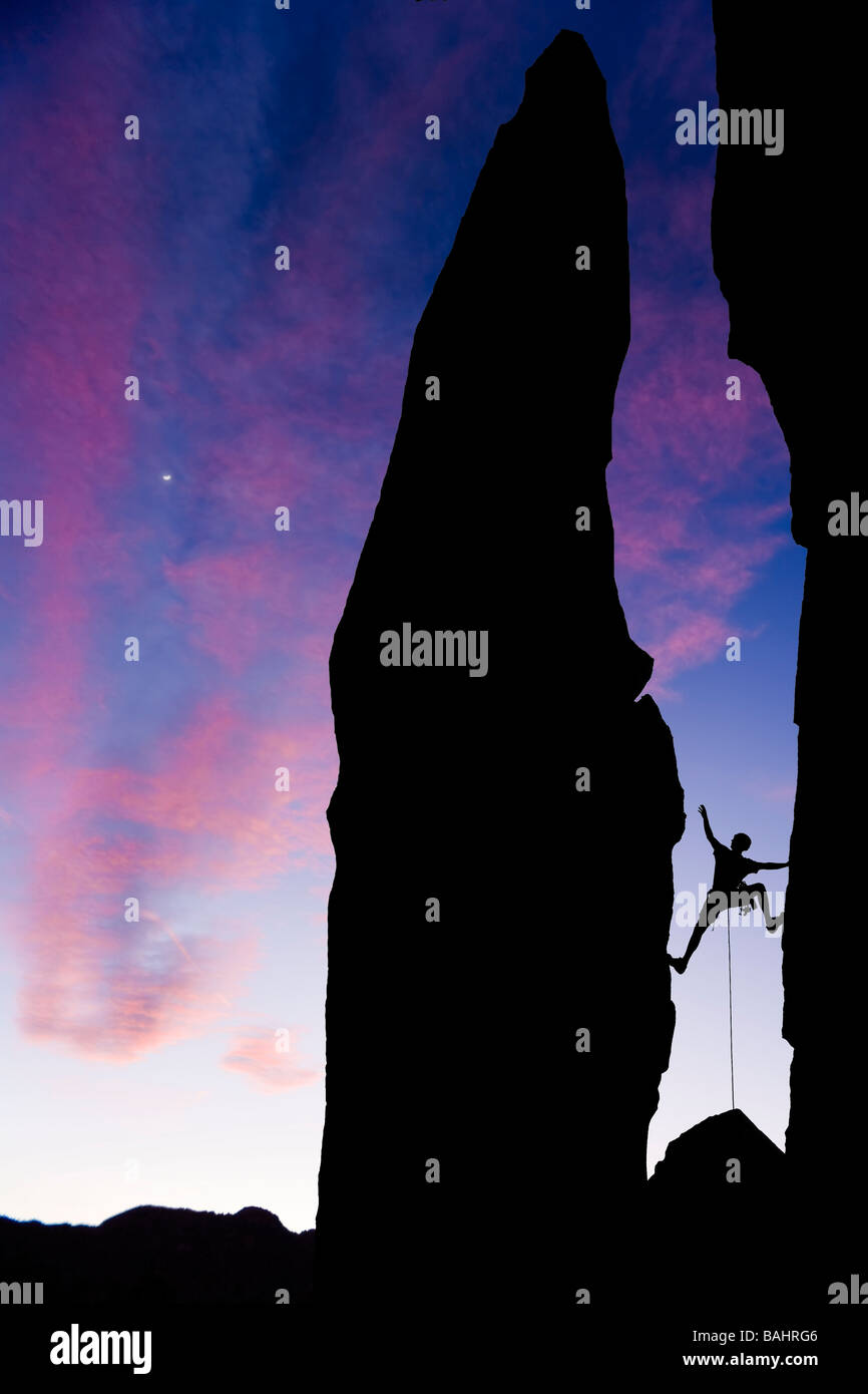 Ein Bergsteiger ist Silhouette, da er über eine Lücke in den Felsen in den Sierra Nevada Mountains Kalifornien erreicht Stockfoto