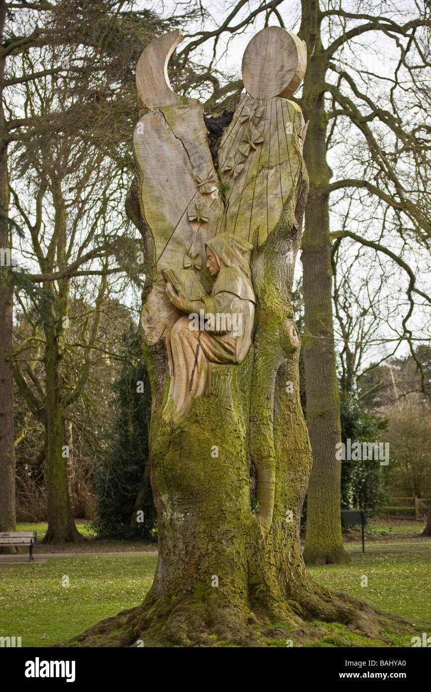 Eine Holzschnitzerei eines Mönchs saß im Baum lesen Stockfoto