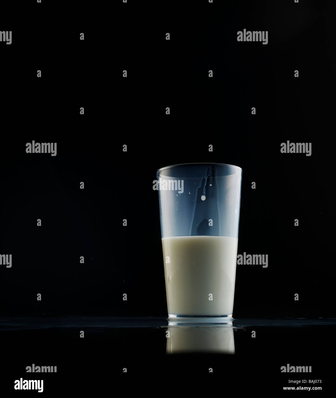 Glas Milch halb, auf einem schwarzen reflektierenden Hintergrund voll Stockfoto