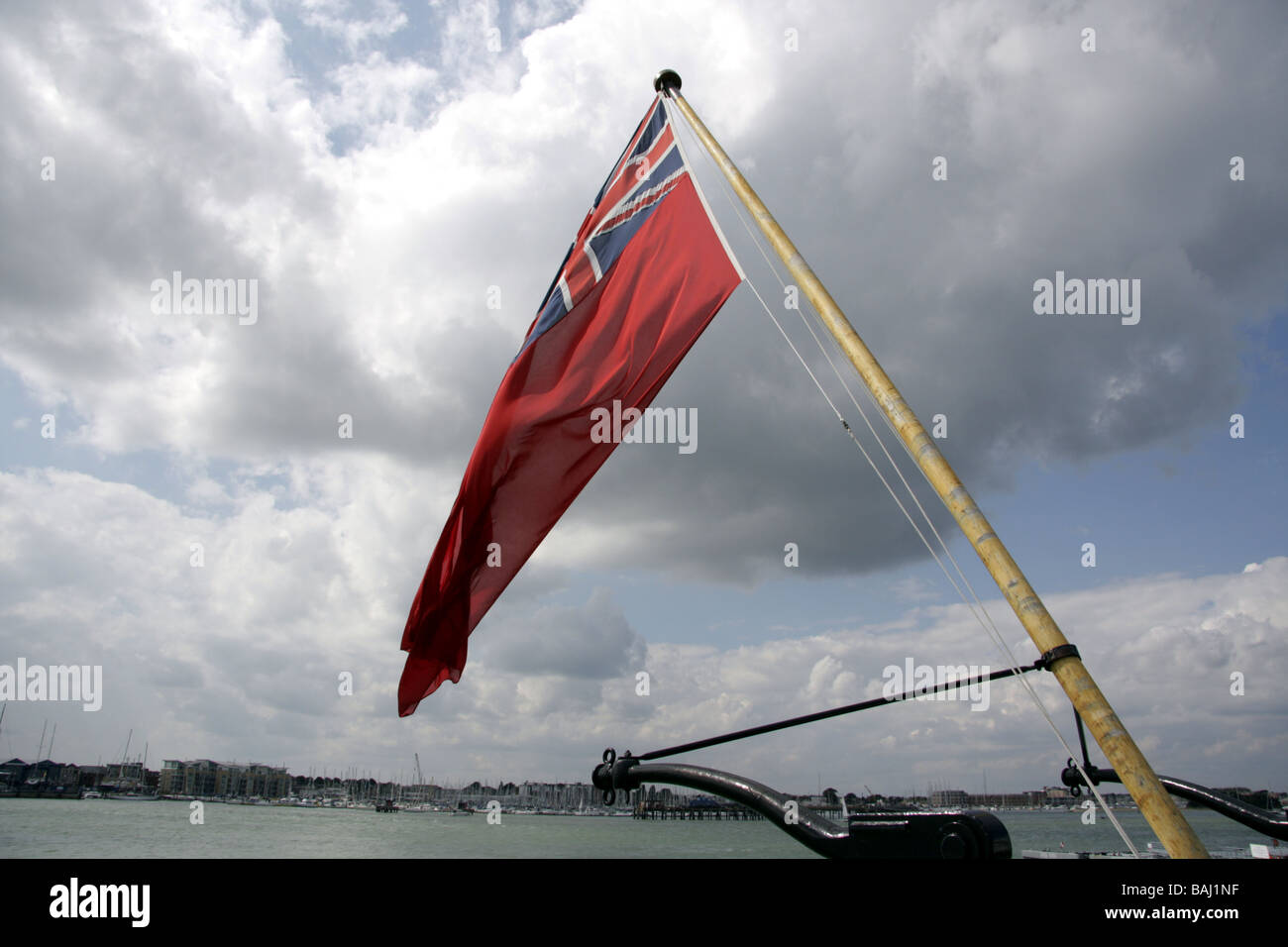 Red Ensign fliegen auf dem Heck der HMS Warrior, zeigt Portsmouth Harbour im Hintergrund Stockfoto