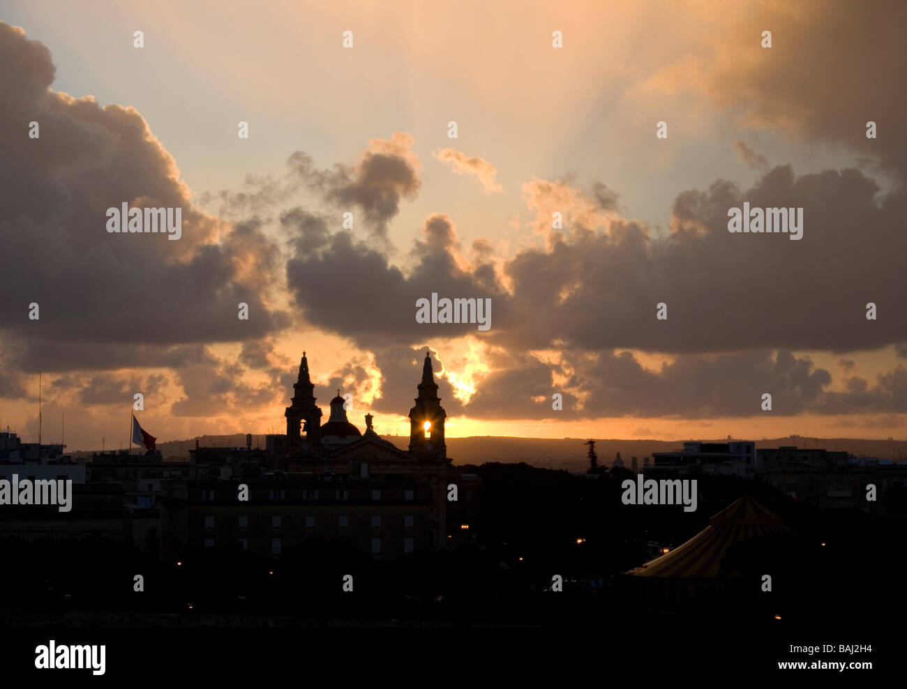Skyline von Malta, Europa, bei Sonnenuntergang mit der untergehenden Sonne sichtbar durch den Glockenturm der Floriana Kirche. Religion und Christentum. Stockfoto