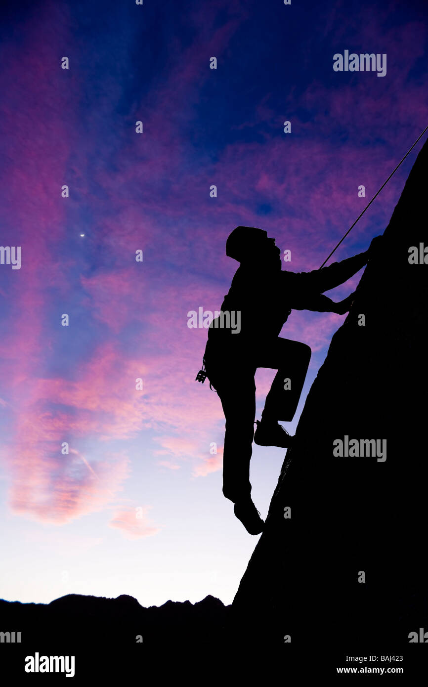 Ein Bergsteiger ist Silhouette, als er seine Weise herauf einen steilen steilen Felswand in den Sierra Nevada Mountains Kalifornien macht Stockfoto