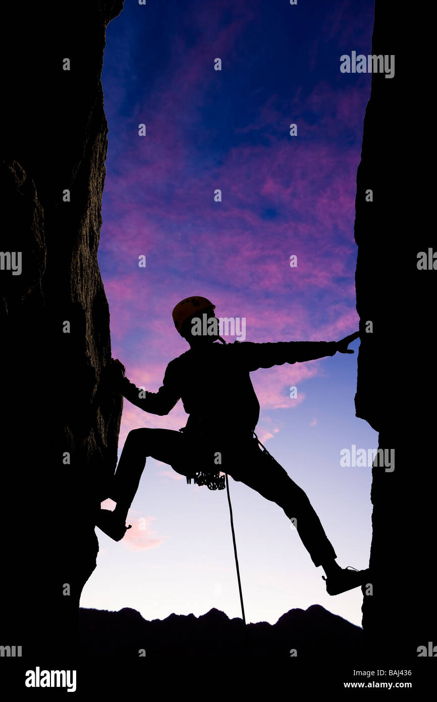 Ein Bergsteiger ist Silhouette, da er über eine Lücke in den Felsen in den Sierra Nevada Mountains Kalifornien erreicht Stockfoto