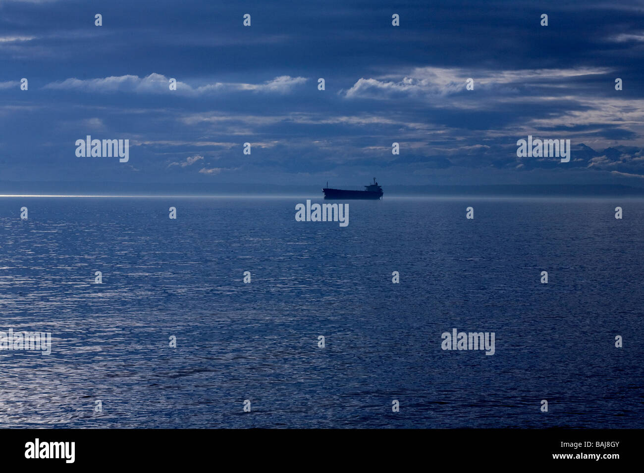 Einsamer Öltanker auf dem Meer in die Straight of Georgia mit ein hoffnungsvolles Licht am Horizont. Stockfoto