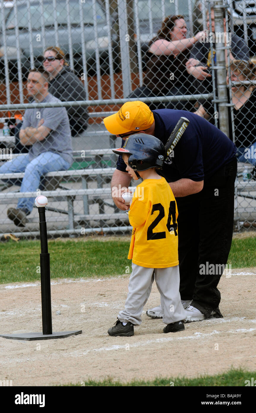 Kleiner Junge bekommen Anweisungen für seinen ersten at bat in Tee-ball Stockfoto