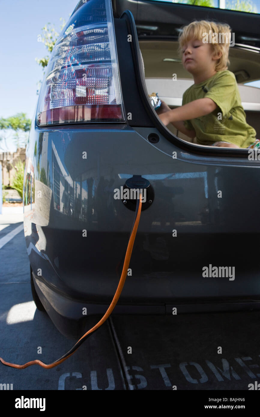 Junge (5-6) sitzt im offenen Kofferraum an Tankstelle Stockfoto