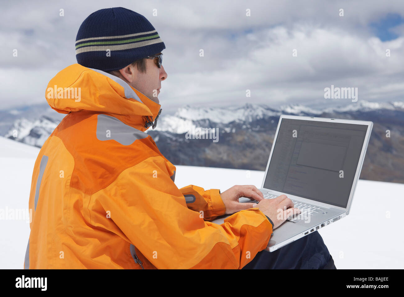 Wanderer mit Laptop auf verschneite Berggipfel Stockfoto