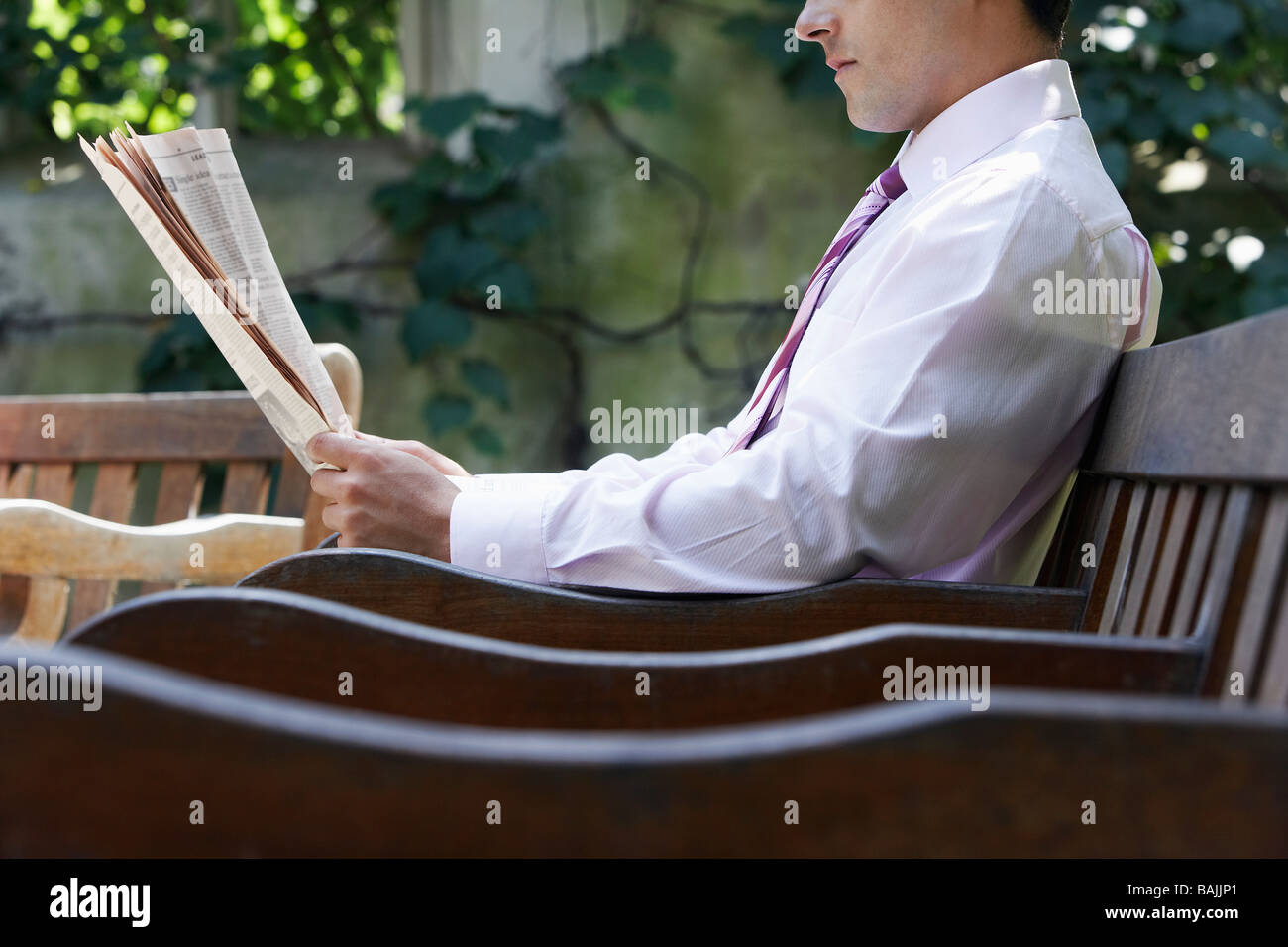 Geschäftsmann, sitzen auf der Bank im Park Garten lesen Papier, Mittelteil Stockfoto