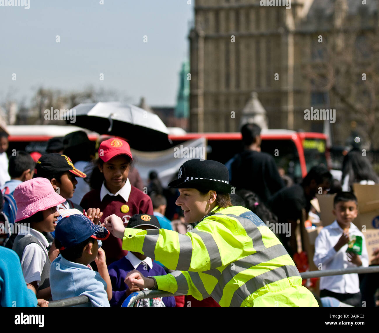 Eine freundliche Metropolitan Policewoman im Gespräch mit tamilischen Schulkindern bei einem Protest in Westminster in London. Stockfoto