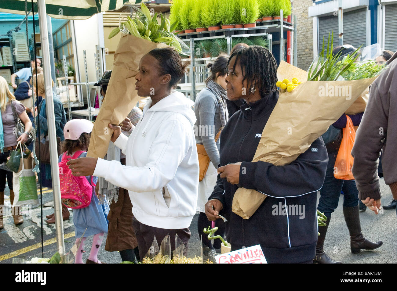 Zwei junge Frauen kaufen Blumen in Columbia Road Sonntag Blumenmarkt Stockfoto