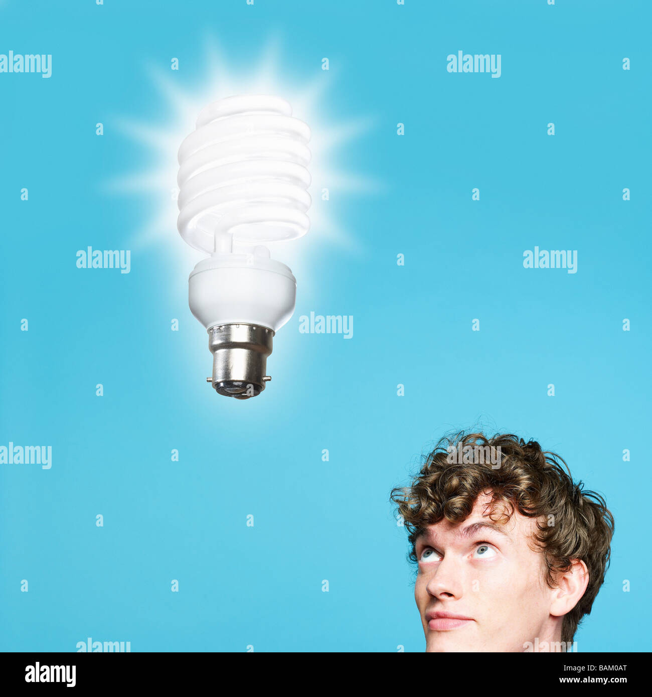Ein junger Mann, Blick auf eine energiesparende Glühbirne Stockfoto