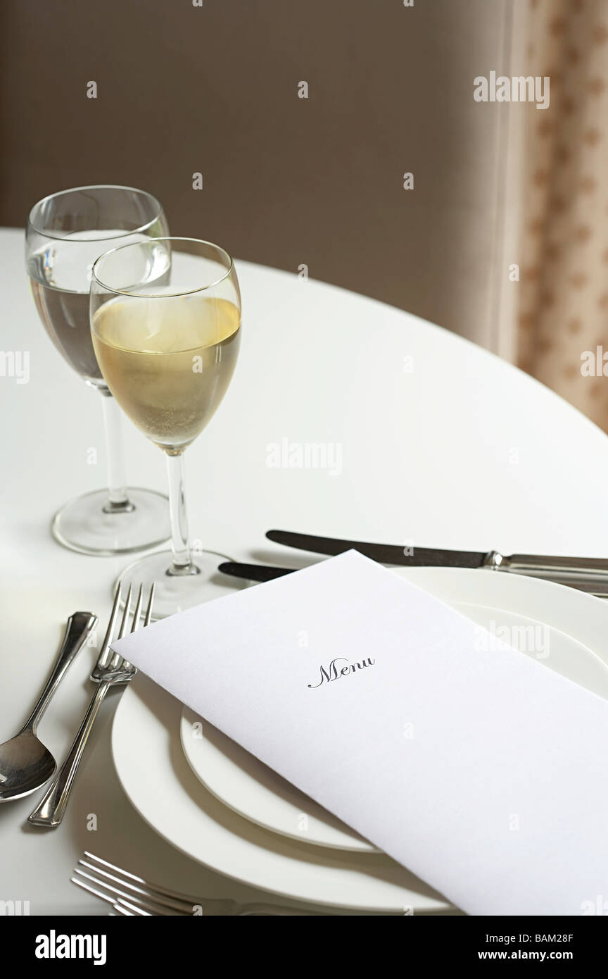 Glas Weißwein und ein Menü auf dem Tisch Stockfoto