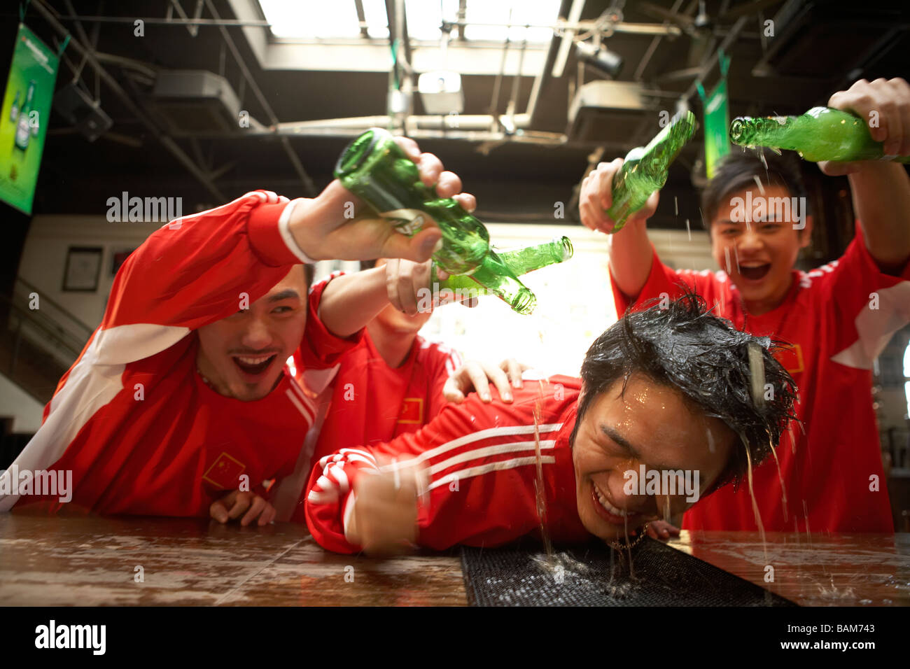 Junge Männer, die Alkohol in Strömen über junge Mann stützte sich auf Bar Stockfoto