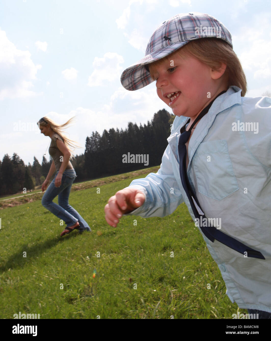 junge zwei Jahre in Folge in der Wiese Mutter im Hintergrund Stockfoto