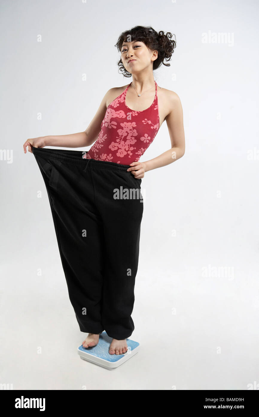 Junge Frau auf Skalen zeigen, Gewichtsverlust Stockfoto