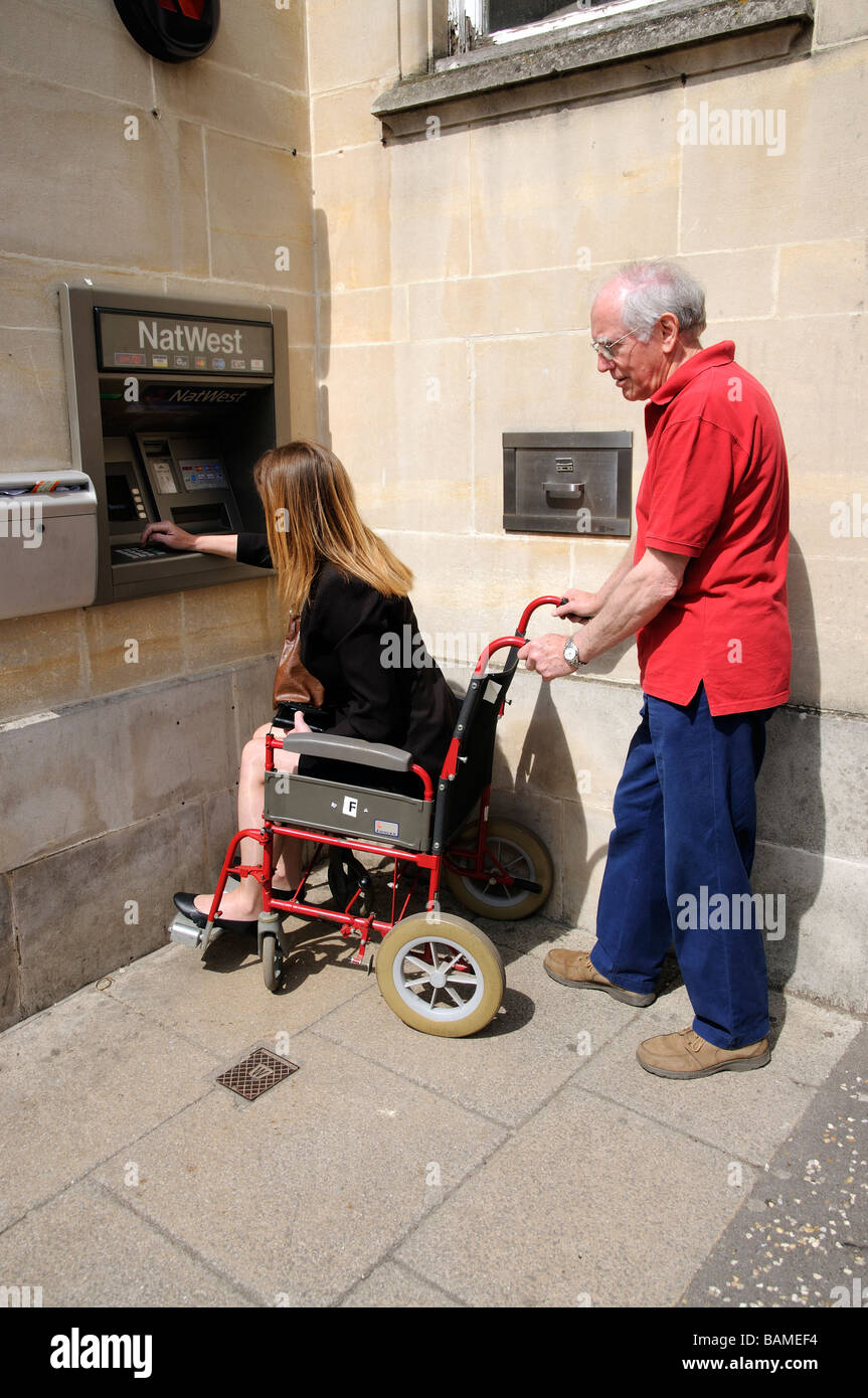 Weibliche ungültig Rollstuhlfahrer und männliche Pfleger mit einer Bank Bargeld darauf England UK Stockfoto