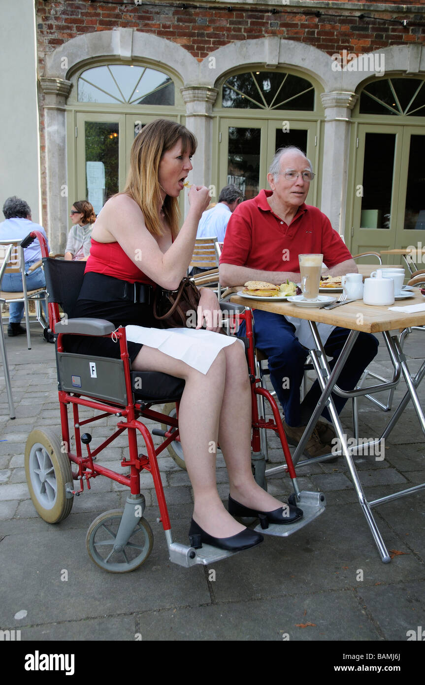 Weibliche ungültig Rollstuhlfahrer mit einer männlichen Pflegekraft genießen eine freien Mittagessen Stockfoto