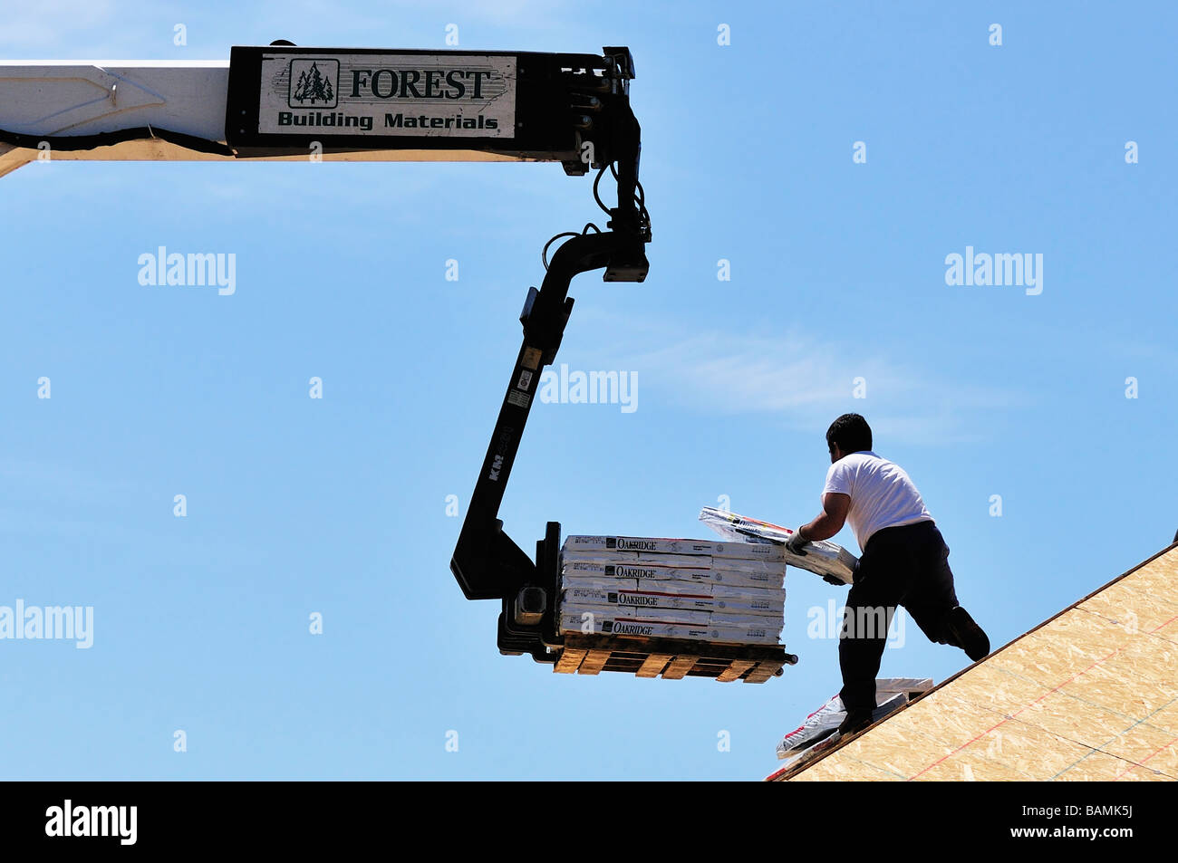 Ein Bauarbeiter entfernt Dachmaterialien aus einer großen Gabelstapler nach oben in ein neues Haus im Bau. Oklahoma City, Oklahoma, USA. Stockfoto
