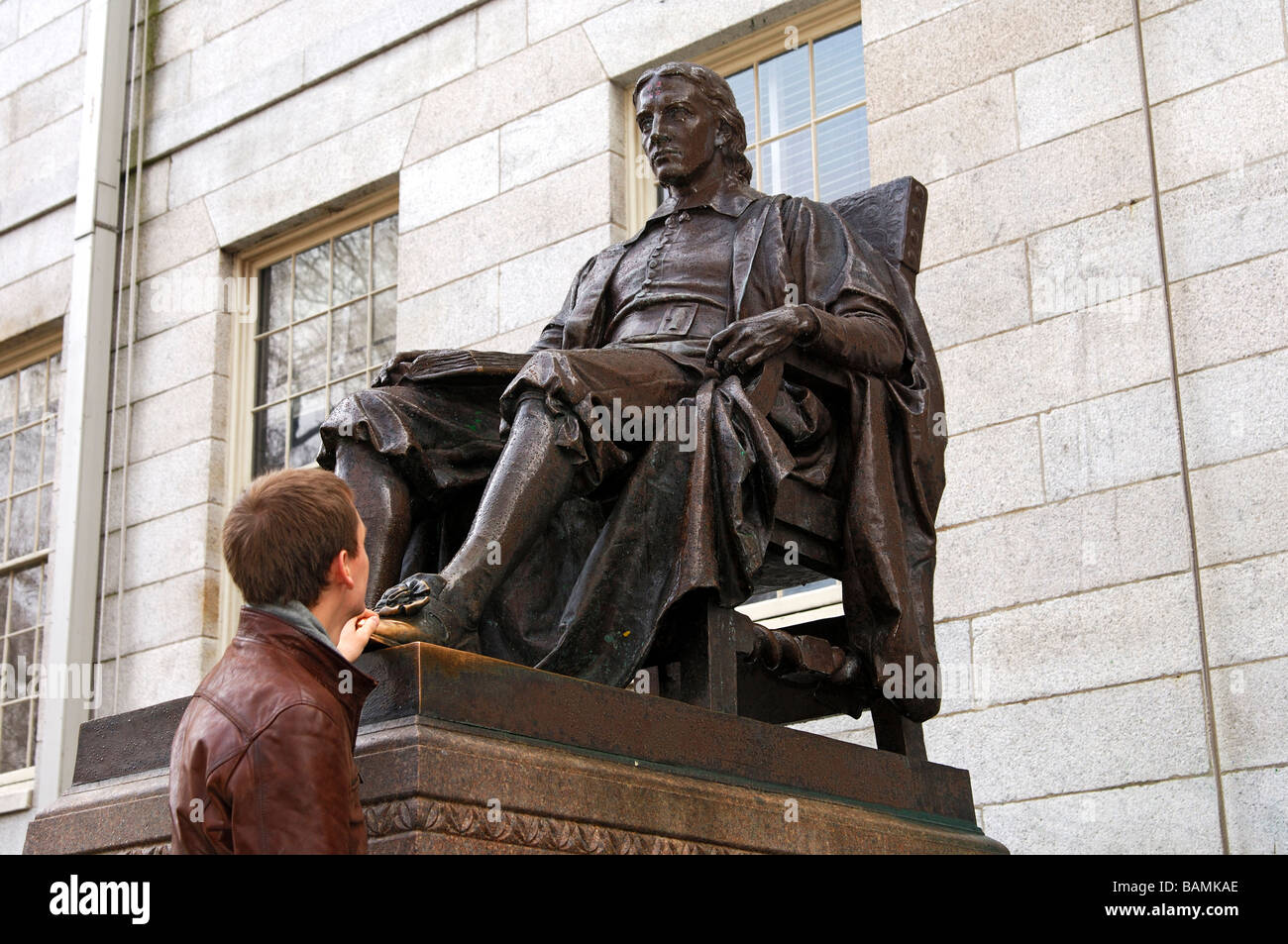 Ein Schüler berühren den linken Schuh von John Harvard als Glücksbringer in Examens, Harvard University, Cambridge, Massachusetts, USA Stockfoto