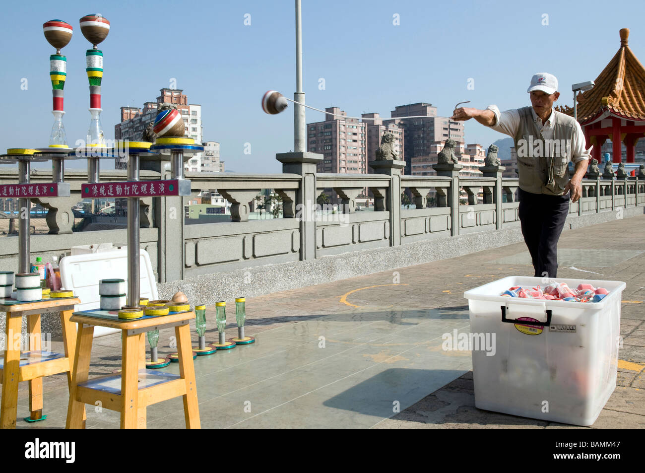 MANN AUF EINER BELEBTEN TOURISTISCHEN BRÜCKE IN SANSIA STADT UND VERKAUF SPINNING TRADITIONELLES HOLZSPIELZEUG DURCHFÜHREN Stockfoto