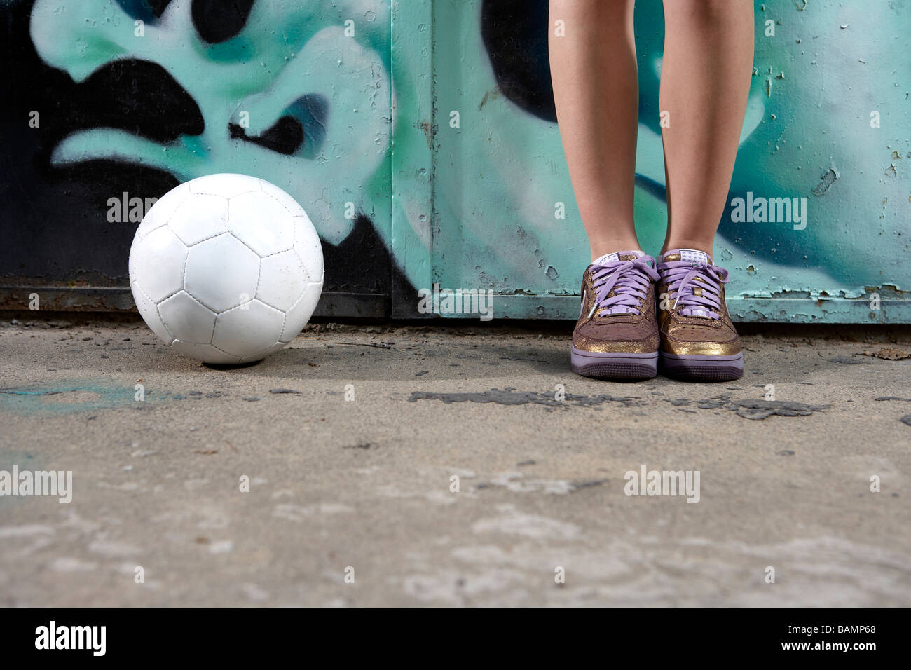 Niedrige Abschnitt Schuss von Teenager tragen Gold Trainer stehen neben Ball Stockfoto