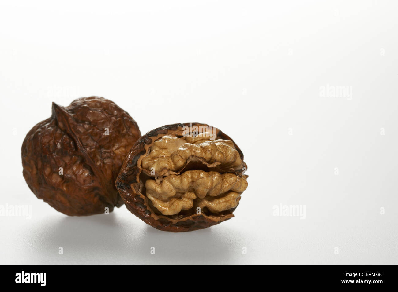 Eine geöffnete und eine ganze Walnuss Stockfoto