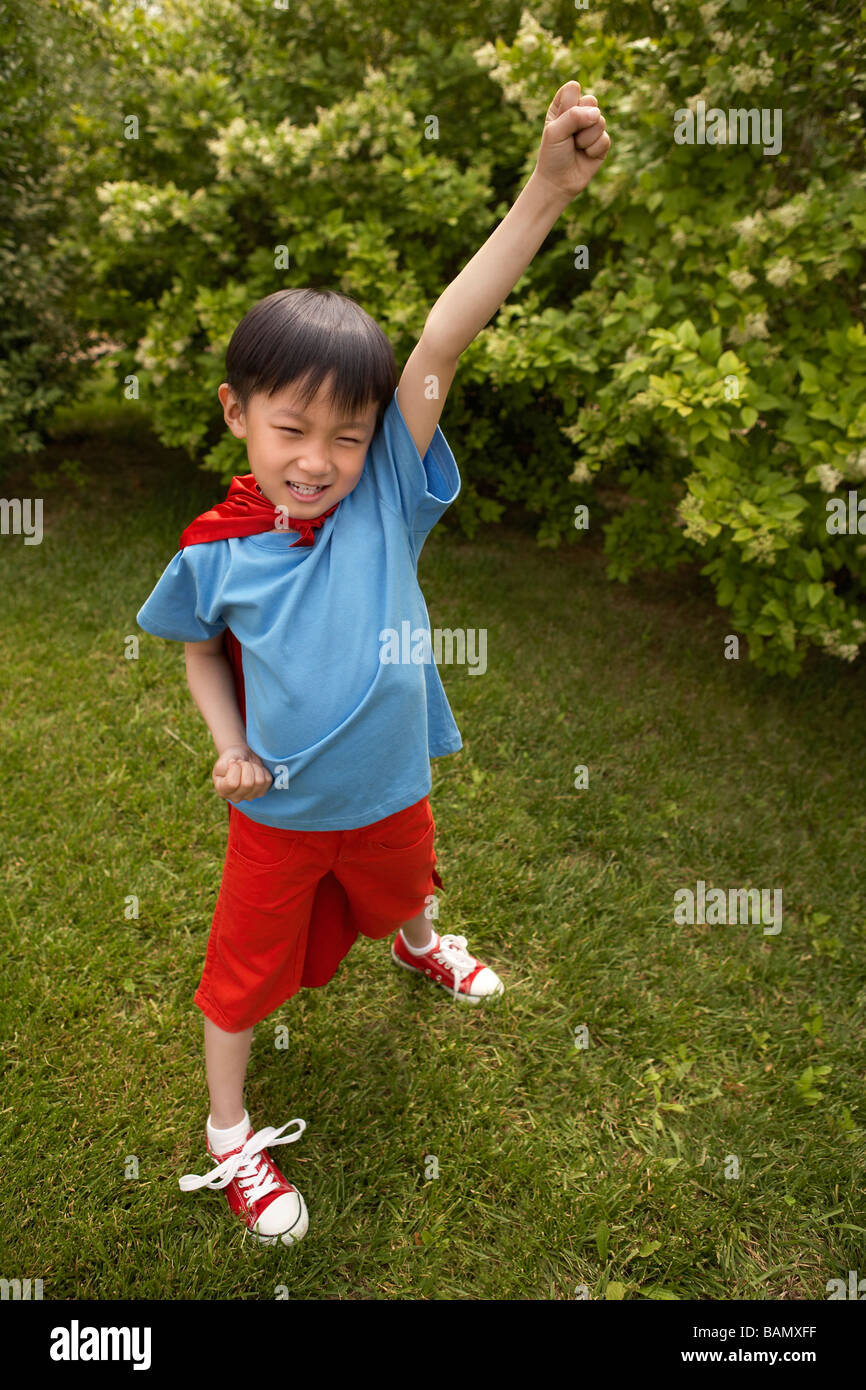 Junge In Red Cape spielen im Garten Stockfoto
