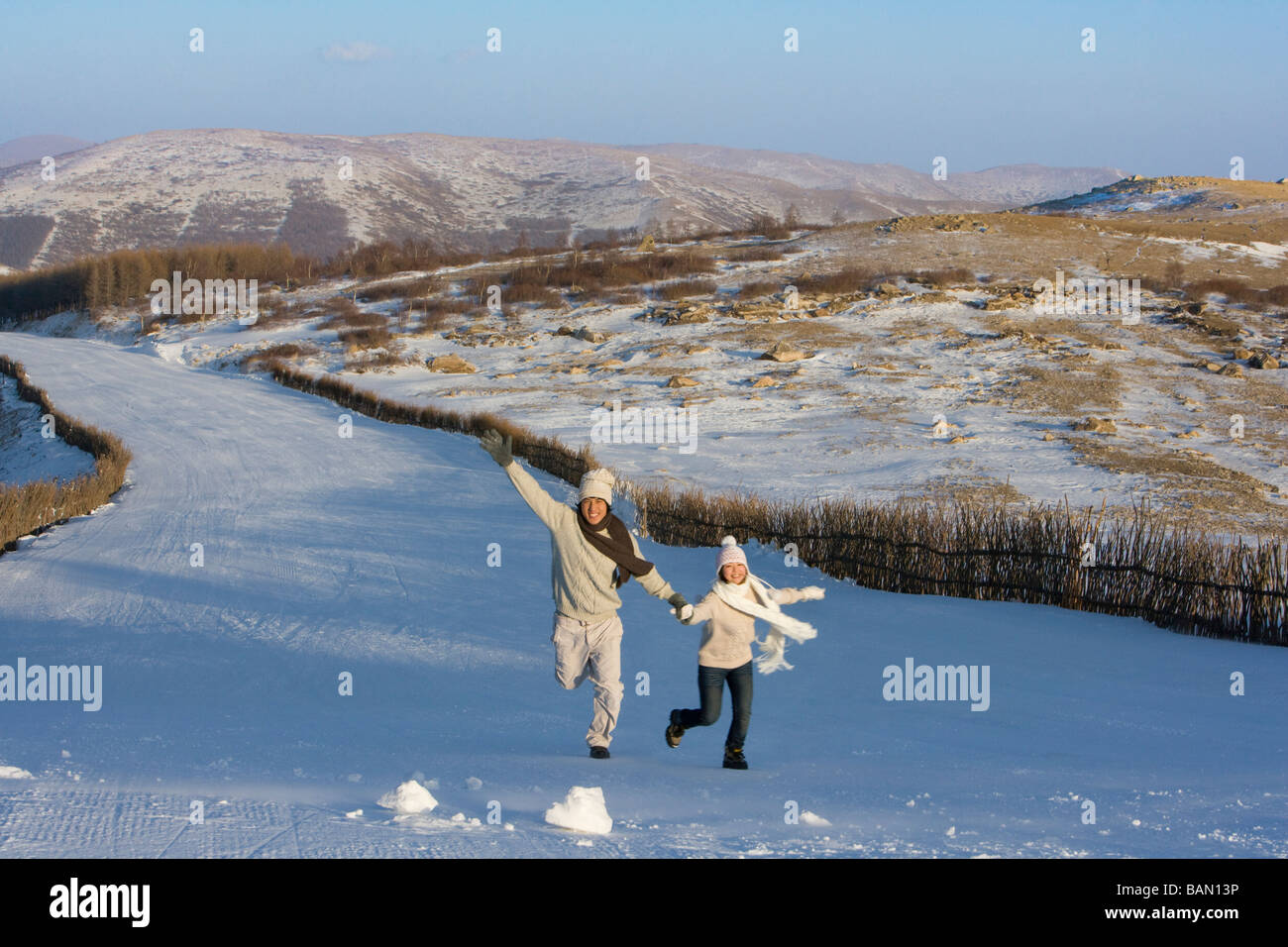 Junger Mann und junge Frau läuft in einer verschneiten Landschaft Stockfoto