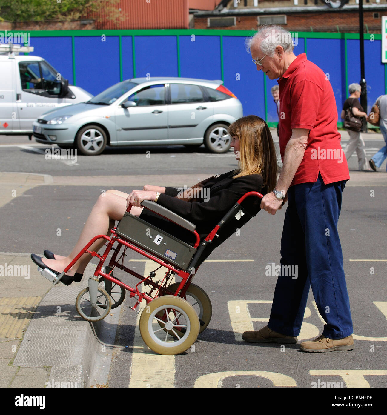 Männliche Pflegekraft rangieren Transit Stil Rollstuhlfahrer und behinderte Frau auf eine Bordsteinkante Stockfoto
