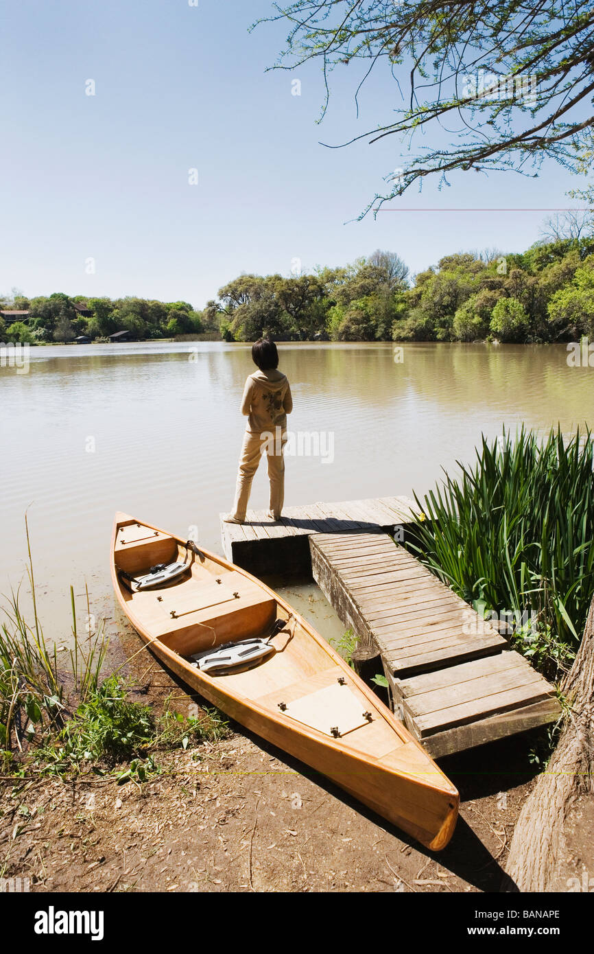 Frau stehend auf Dock neben Kanu Stockfoto