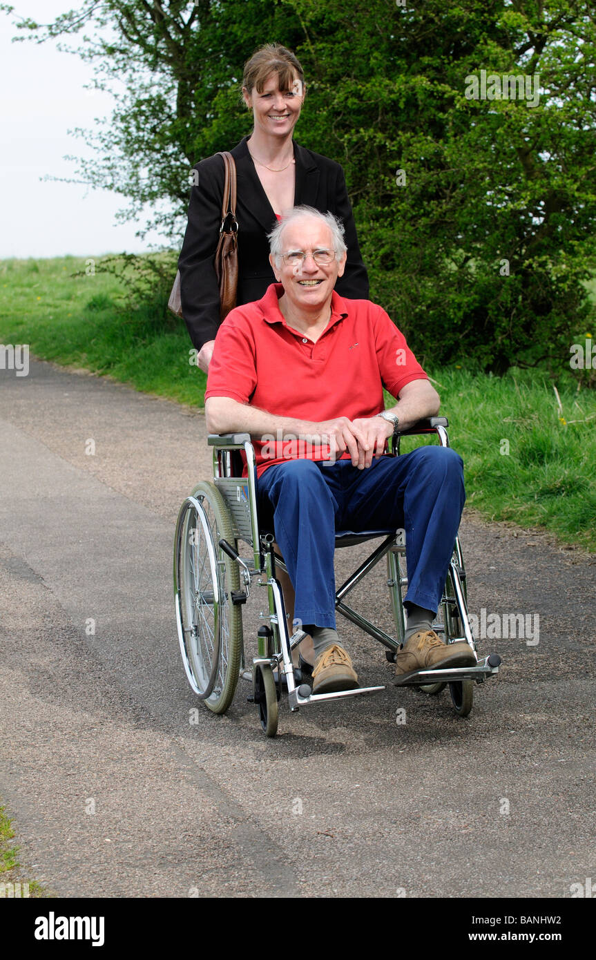 Weibliche Pflegeperson drängen älteren Mann im Rollstuhl auf dem englischen Land UK Stockfoto