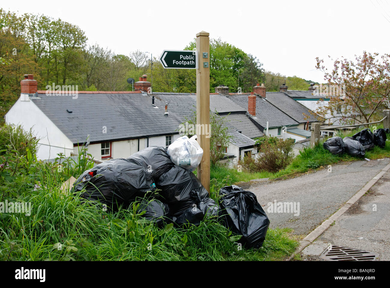 schwarzer Kunststoff Mülltüten links außen Cottages in Cornwall, Großbritannien Stockfoto