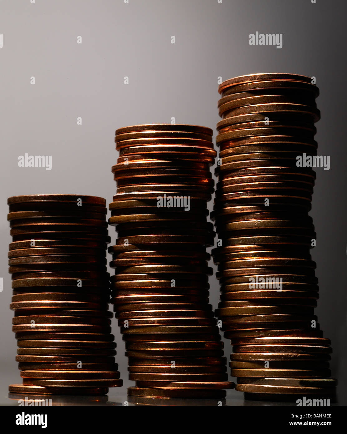 Drei Stapel von Pennys auf grauem Hintergrund mit Highlight links Stockfoto