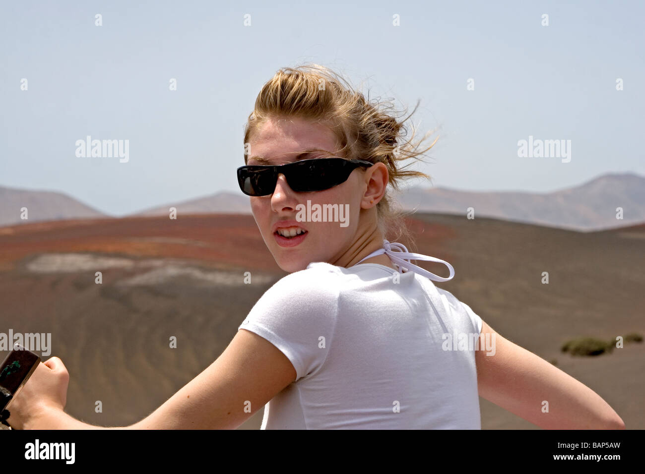 Teenager-Mädchen reiten auf einem Kamel Zug auf Lanzarote mit Hügeln in der Ferne die Sonne genießen Stockfoto