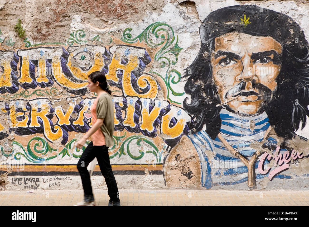Eine Frau in einer Straße von San Telmo Bezirk mit dem Che Guevara-Porträt gemalt auf einer Wand hinter, Buenos Aires, Argentinien Stockfoto
